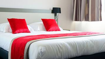 A neatly made bed with white and red bedding, a grey headboard, and a black lamp on the wall.