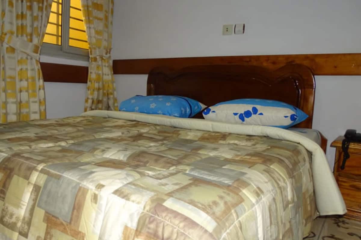 A bed with a wooden headboard, two pillows, and a quilt.