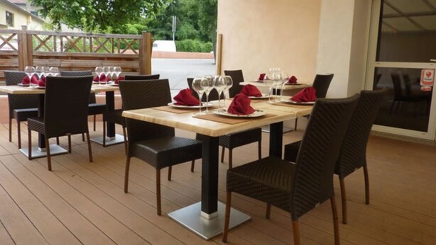 An outdoor dining area with tables set for two, each with a pair of chairs, and a wooden deck flooring. - Residence Hotel Badjo (Abidjan)