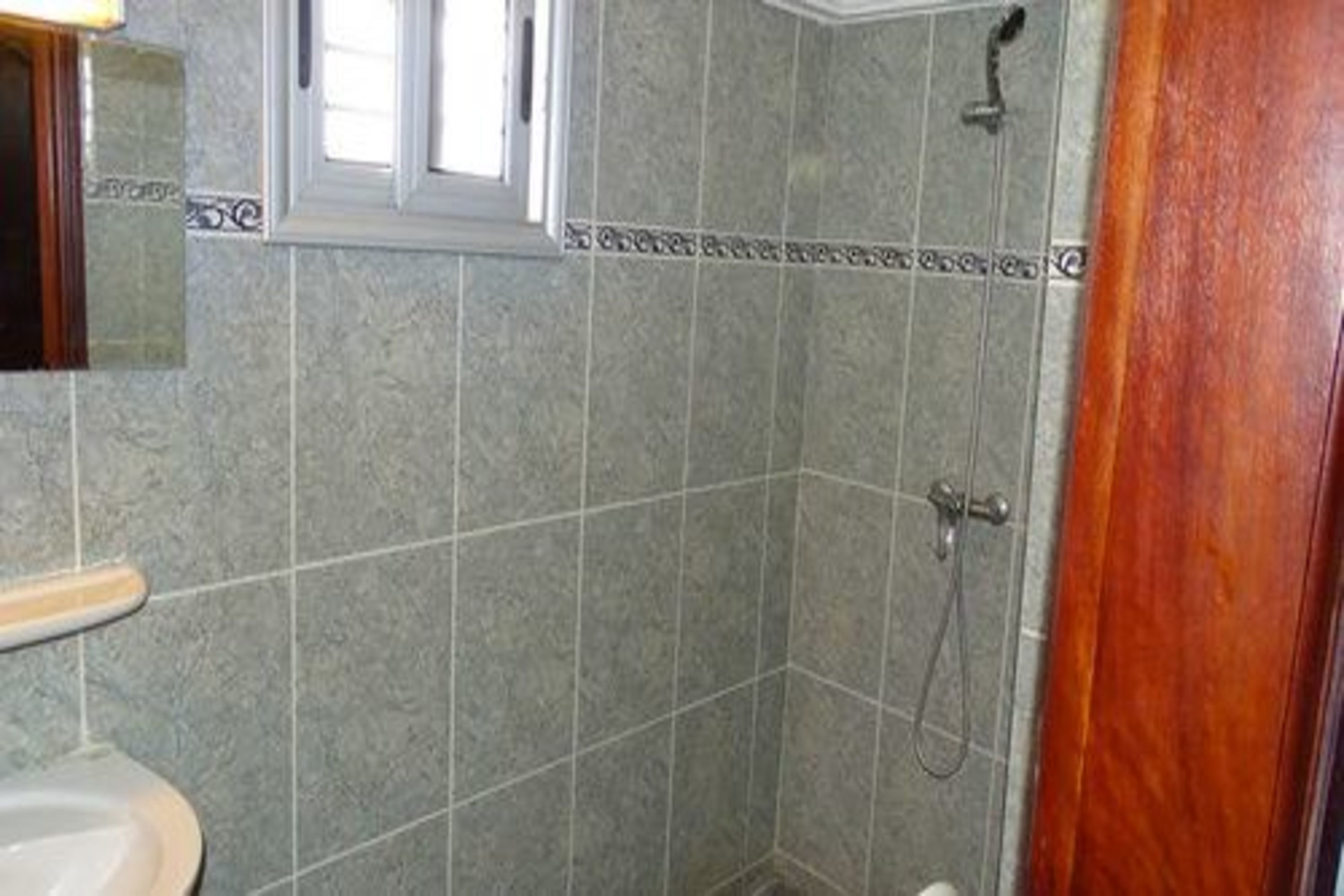 Un baño con ducha, inodoro y ventana.