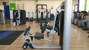 A gym with various exercise equipment, including a bench press, a squat rack, and cardio machines. - Residence Hotel Badjo (Abidjan)