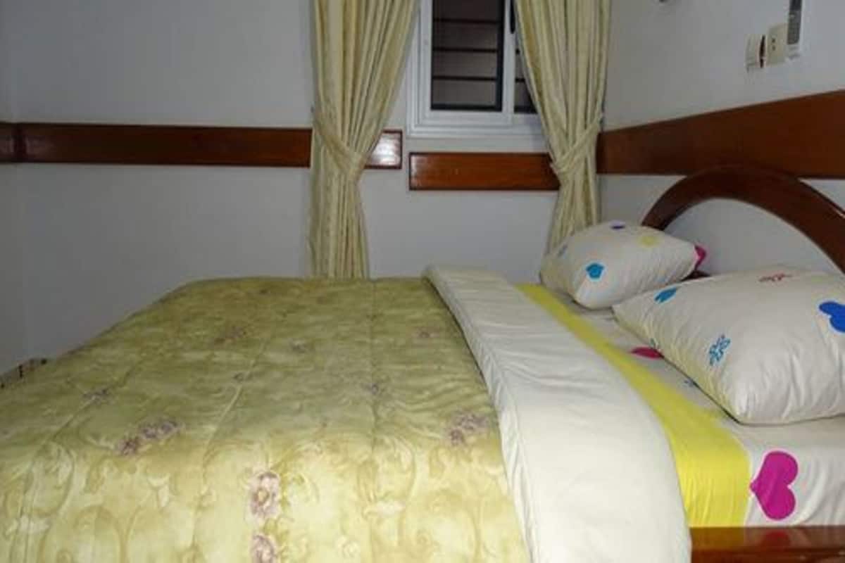 A bed with a floral bedspread, a wooden headboard, and decorative pillows with heart patterns.