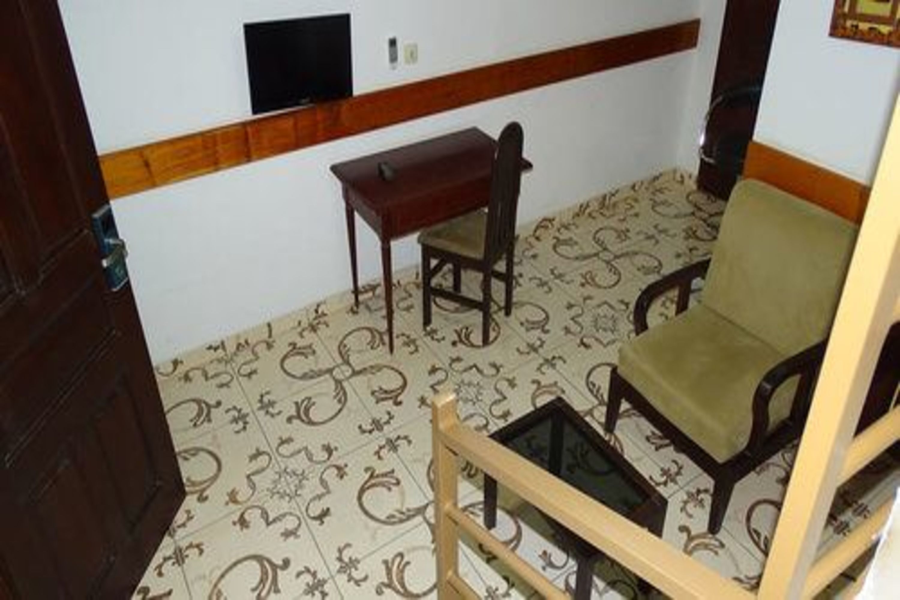 A room with a patterned floor, a wooden desk, a chair, and a sofa.