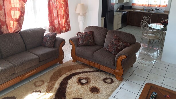 A living room with two sofas, a patterned rug, and a dining area with a table and chairs. - Personal Touch Studio (Nassau)