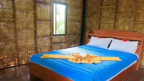 Cama bem arrumada com colcha azul e toalha decorativa, em frente a parede com padrão tecido.