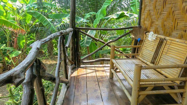 Um deck de madeira com uma cadeira de bambu e um painel trançado.
