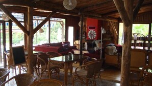 A rustic wooden interior with wicker furniture, a fireplace, and large windows. - Likya Lodge Adrasan (Kumluca)