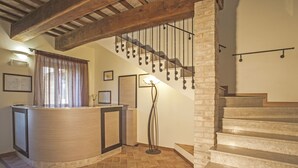 Ein Empfangsbereich mit Holztresen, einer Stehlampe und einer Treppe mit Metallgeländer.