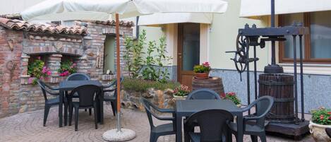 Un patio al aire libre con pared de ladrillo, chimenea de piedra y cocina rústica al aire libre.