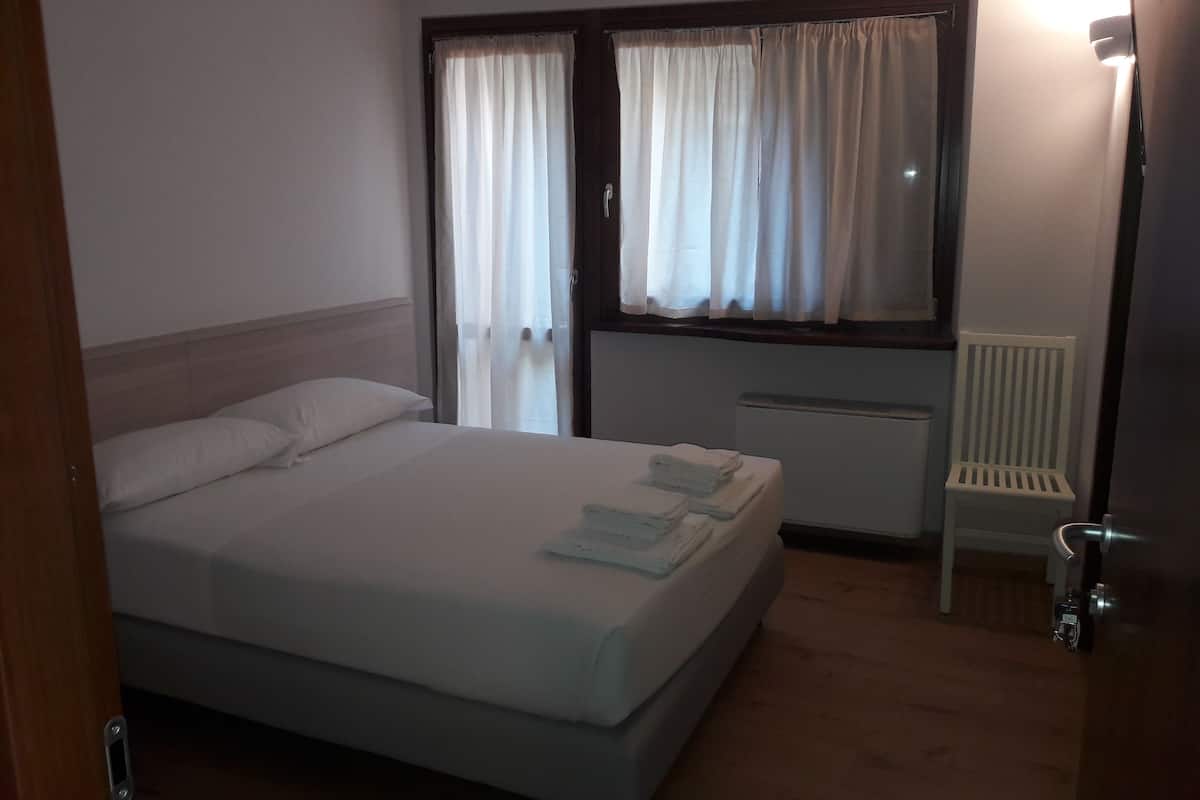 Ein Hotelzimmer mit Bett, Sessel, Heizkörper und Vorhängen.