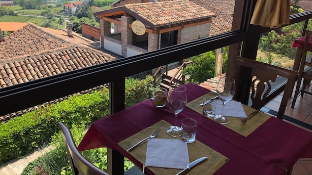 Une table à manger installée de manière à offrir une vue sur un paysage rural, avec des champs en terrasses et des bâtiments traditionnels.