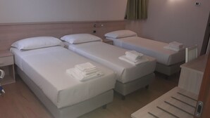Une chambre d’hôtel avec deux lits simples, un petit bureau, une chaise et un radiateur.
