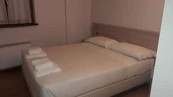 A single bed with a wooden headboard, a bedside table with a lamp, and a window with curtains.