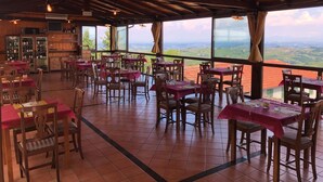 Un restaurant avec des tables et des chaises en bois, de grandes fenêtres donnant sur la campagne.