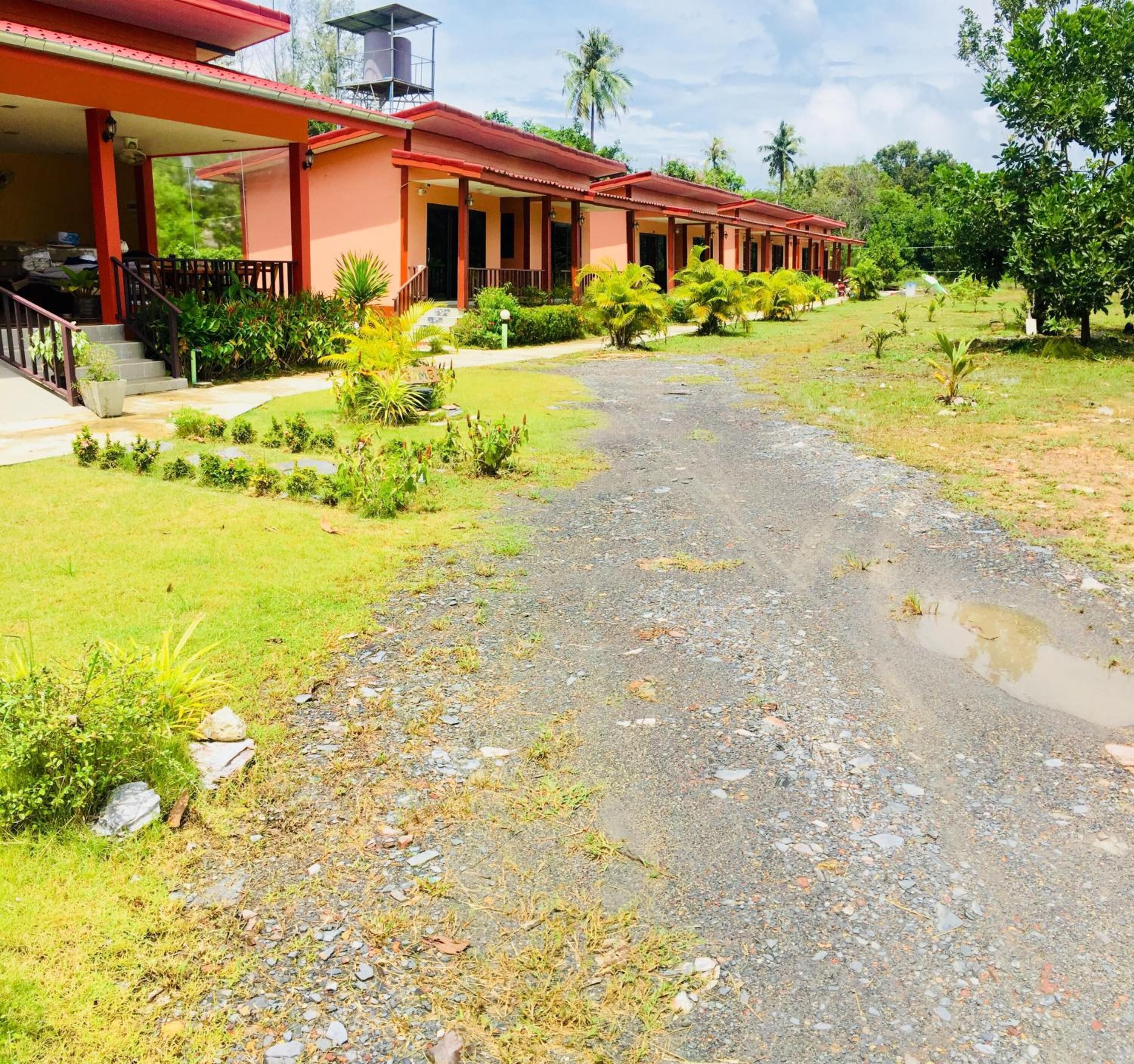A row of red-roofed buildings with a gravel path leading to the entrance.