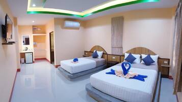 A hotel room with two beds, a small kitchenette, a mirror, and an air conditioning unit.