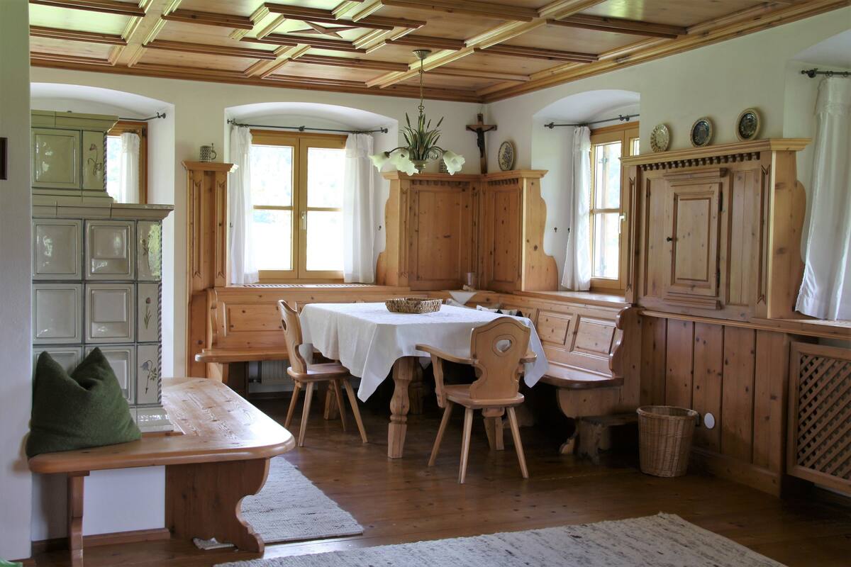 Uma sala de jantar tradicional com mobiliário de madeira, uma mesa coberta por uma toalha branca e um banco.