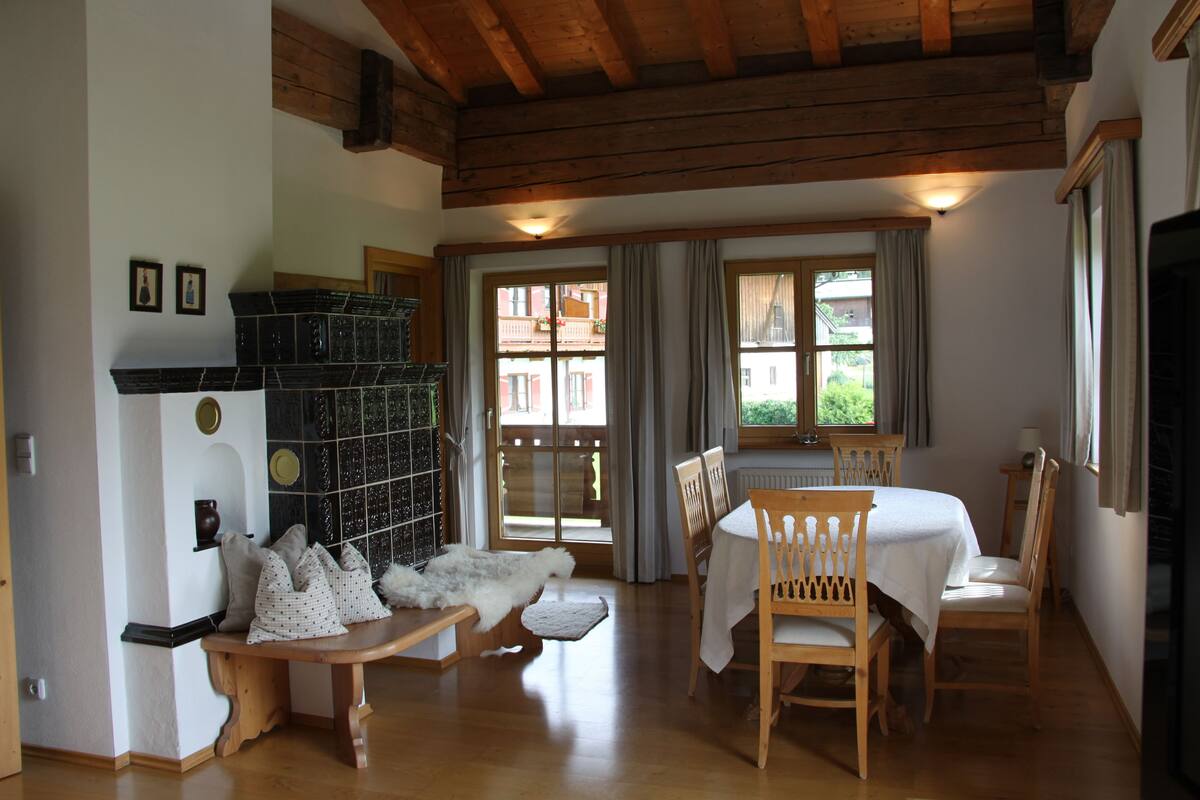 Um quarto acolhedor com teto de madeira, uma mesa de jantar com cadeiras, um banco e uma lareira com caixas de armazenamento.