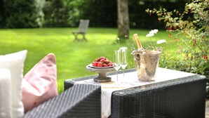 Une table en osier, sur laquelle se trouvent un saladier rempli de fraises, un verre de champagne et un chandelier.