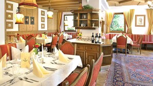 Un restaurant au décor intérieur en bois, doté de nombreuses tables et de chaises à revêtement rouge.