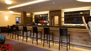 Un espace bar moderne avec des tabourets de bar en bois, un comptoir et un escalier menant à un niveau supérieur.