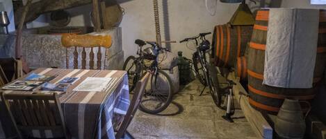 A rustic room with a wooden table, chairs, bicycles, and a barrel.