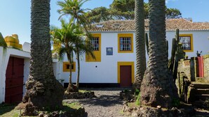 Un bâtiment traditionnel doté d’une cour pavée, de palmiers et d’un toit en tuiles.