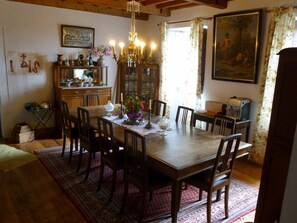 Une salle à manger avec une table en bois, des chaises, un lustre et un arrangement floral.