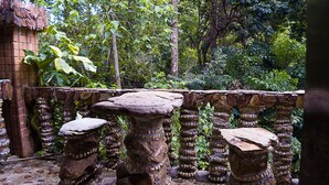 Um parapeito de pedra com esculturas detalhadas e uma mesa de pedra rústica em um jardim exuberante.