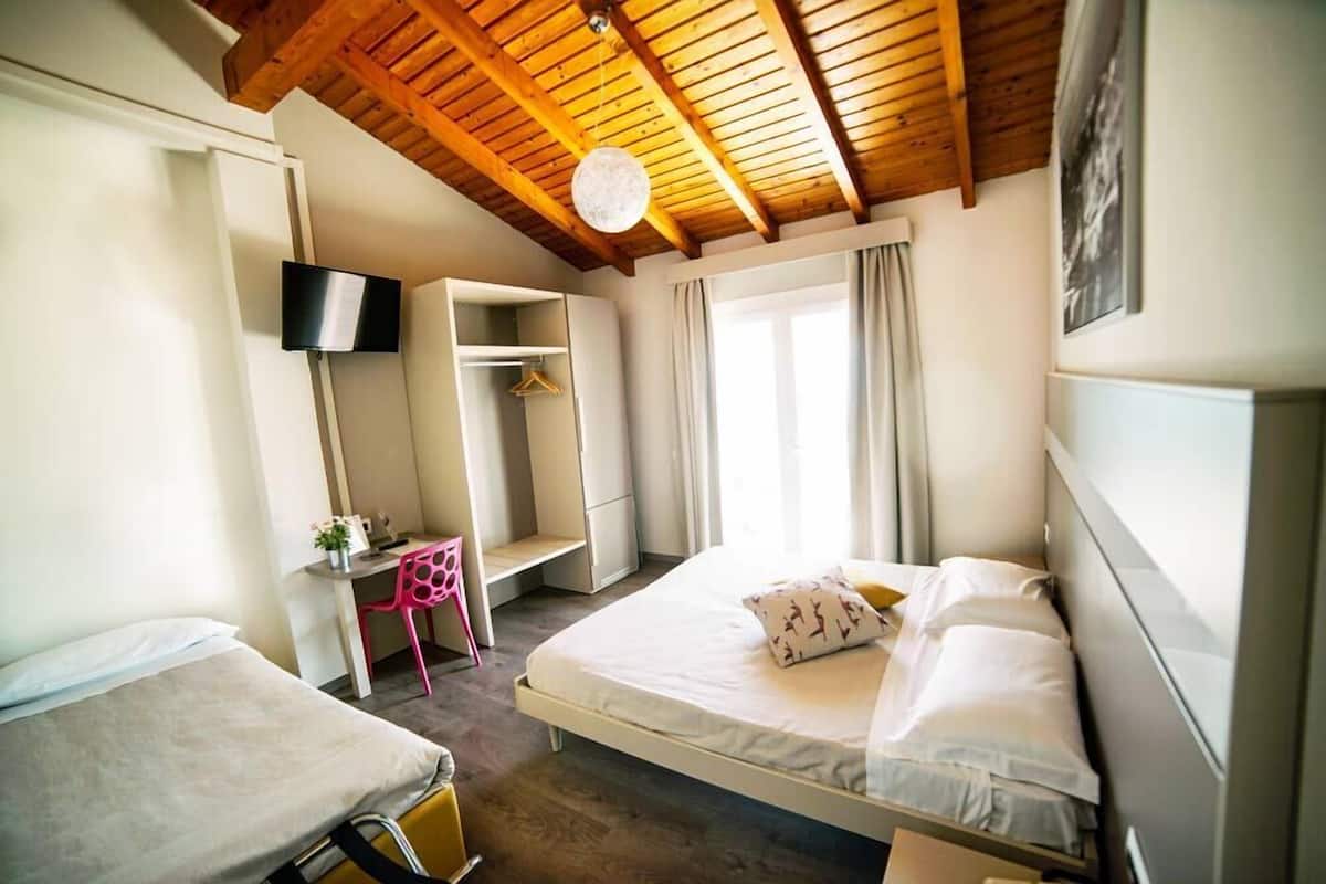 A bedroom with two beds, a desk, a TV, and a wardrobe.
