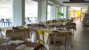 Un restaurante espacioso con múltiples mesas y sillas, ventanas amplias y un interior moderno y cuidado.