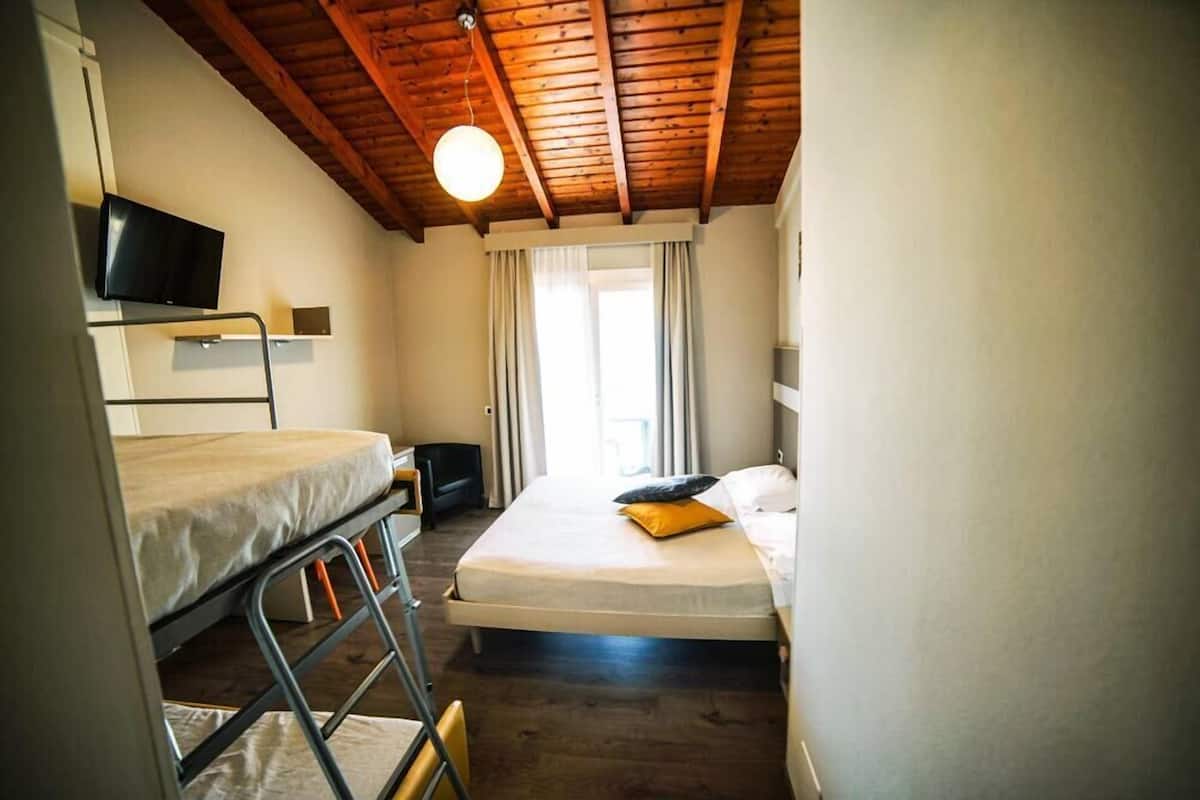 A compact room with bunk beds, a television, and a window with curtains.