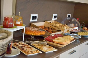 Un buffet proposant une variété de plats, notamment des pâtisseries, du pain et des condiments.