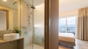 Un baño moderno con ducha de mampara de vidrio, un lavamanos y un espejo grande.
