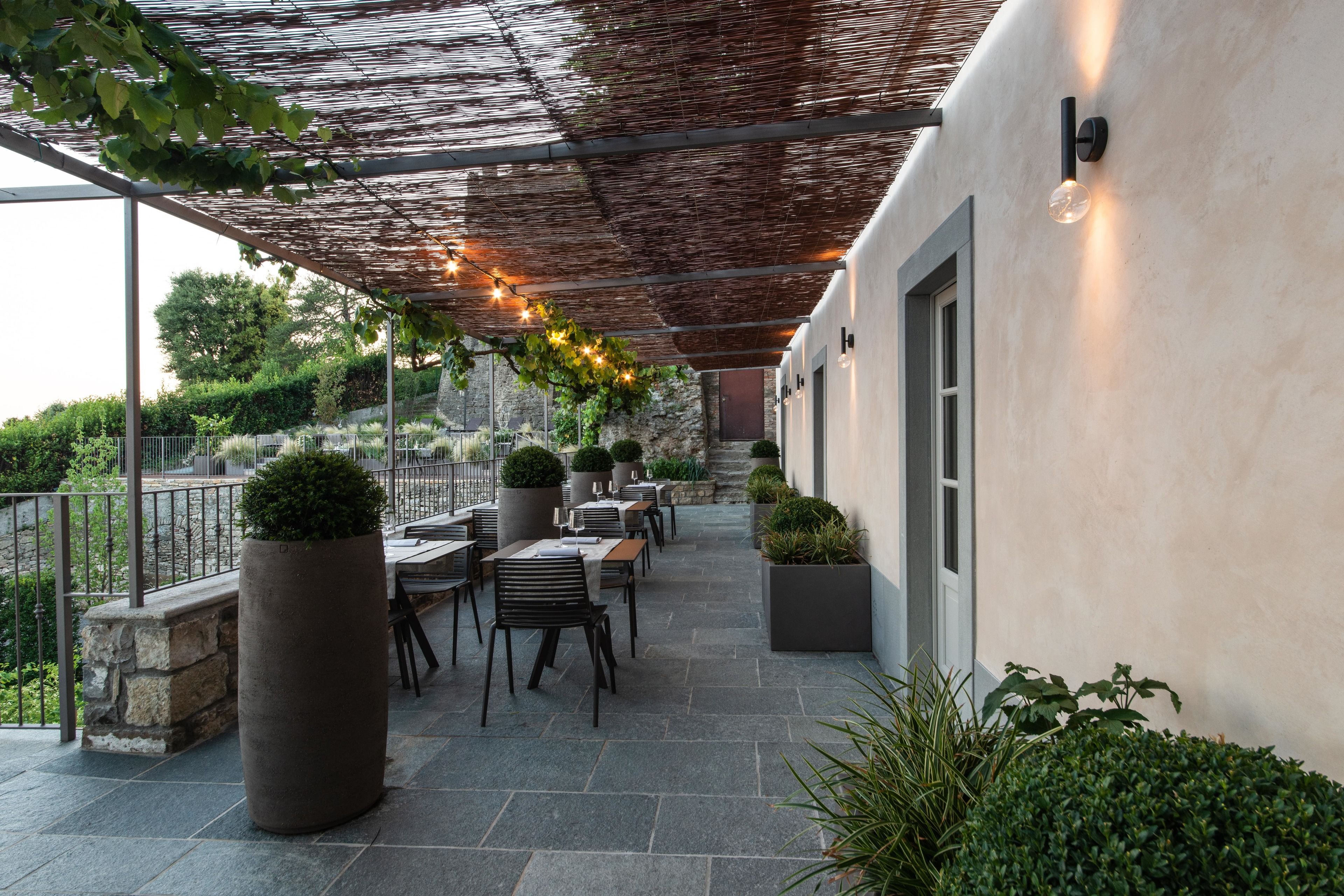 An outdoor patio with stone flooring, wooden furniture, and potted plants.