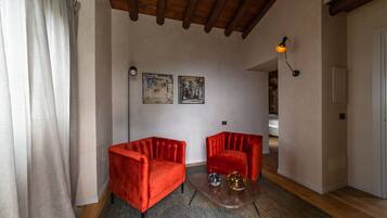 Un salón con dos sillones tapizados de terciopelo rojo, una mesita de centro con adornos y un techo de madera.