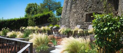 A stone tower, outdoor seating area with chairs, and potted plants.