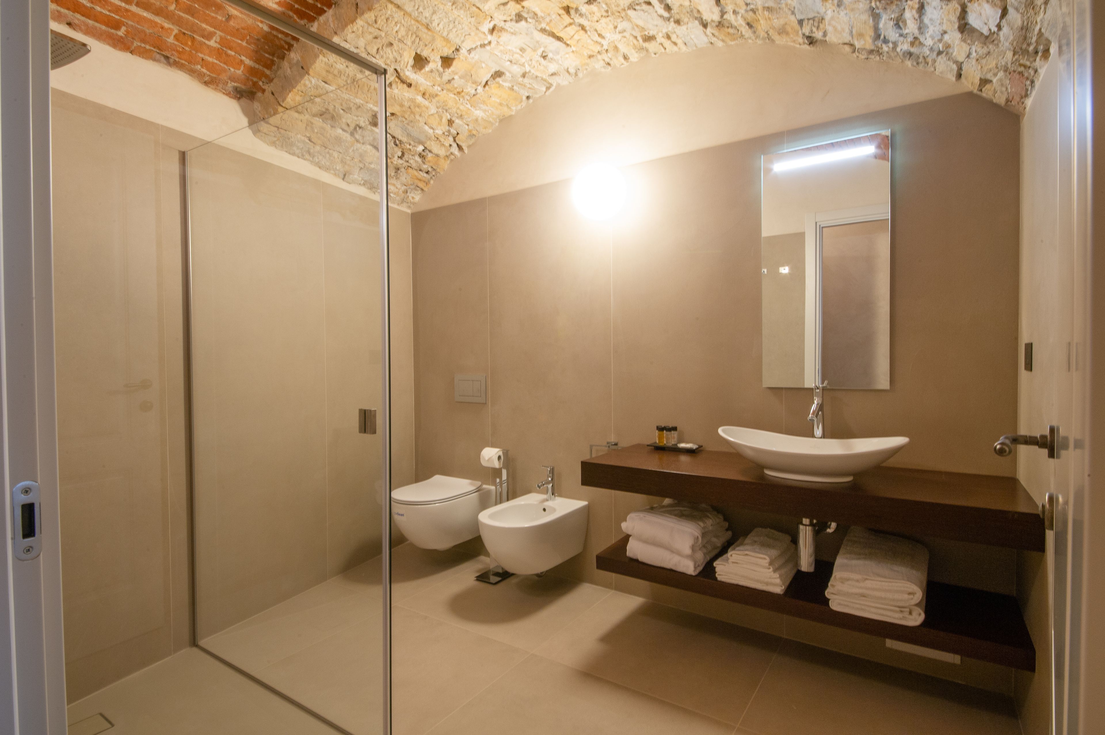 Un baño moderno con cabina de ducha de vidrio, un lavabo blanco y un bidé.