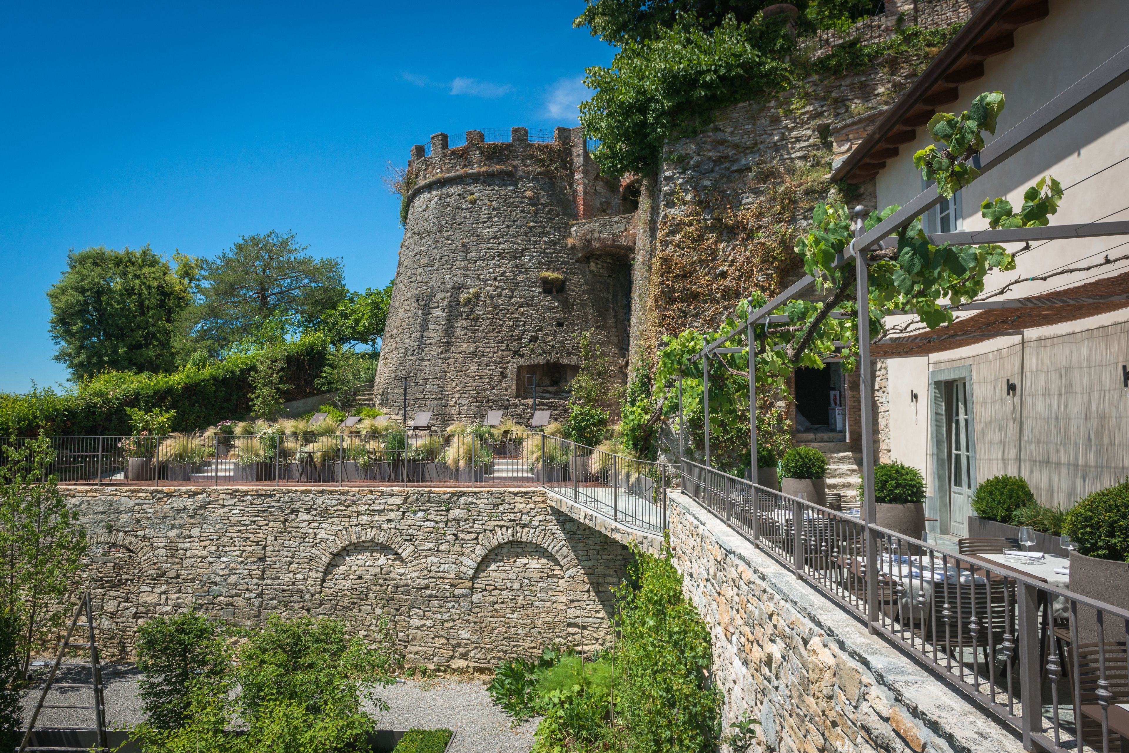 A stone castle with a balcony overlooking a garden.