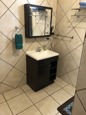Une salle de bain avec un meuble-lavabo noir, un lavabo blanc, un miroir et un porte-serviettes.