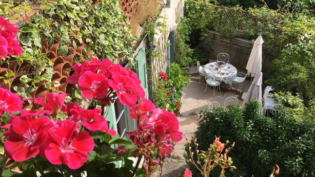 A patio with a table and chairs, surrounded by potted plants and flowers. - Les Asphodeles (Saint-Hippolyte-du-Fort)