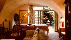 A cozy room with a high arched ceiling, a dining table with chairs, a sofa, and a lamp. - Les Asphodeles (Saint-Hippolyte-du-Fort)