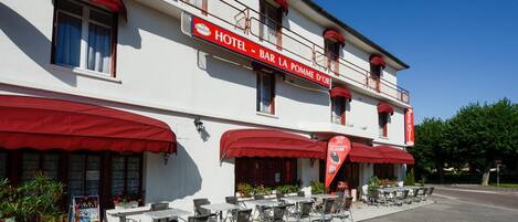 A hotel with outdoor seating and a red awning.