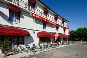 Un hotel con terraza al aire libre y un toldo rojo.