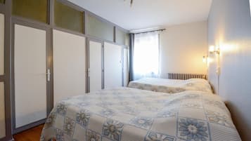 A bedroom with a bed, a radiator, and a window with curtains.