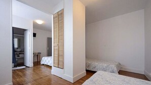 Ein Schlafzimmer mit zwei Betten, einem Kleiderschrank und einem durch eine offene Tür einsehbaren Badezimmer.