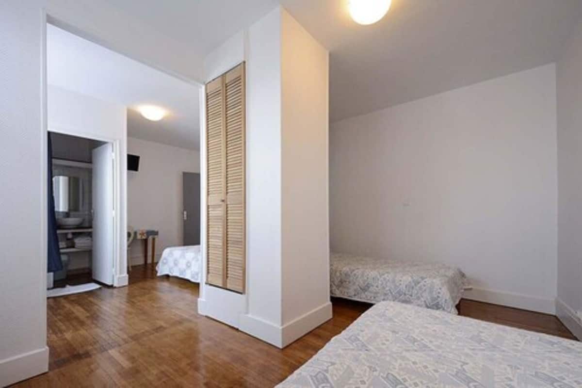 Ein Schlafzimmer mit zwei Betten, einem Kleiderschrank und einem durch eine offene Tür einsehbaren Badezimmer.