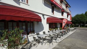 Ein Hotel mit Außenbestuhlung und roten Markisen.