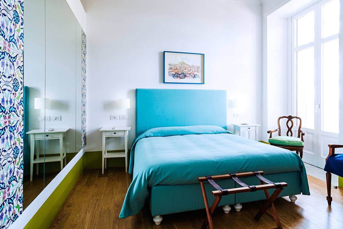 A bedroom with a bed, bedside tables, a chair, and a window.