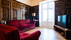 A living room with a red sofa, a television, and wooden paneling.